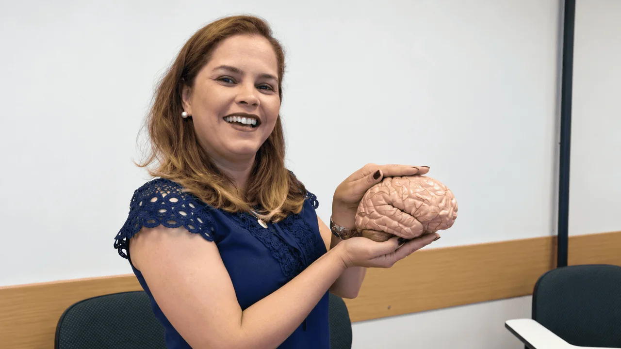 Andreia Luana Martins segurando um modelo anatômico de cérebro em sala de aula